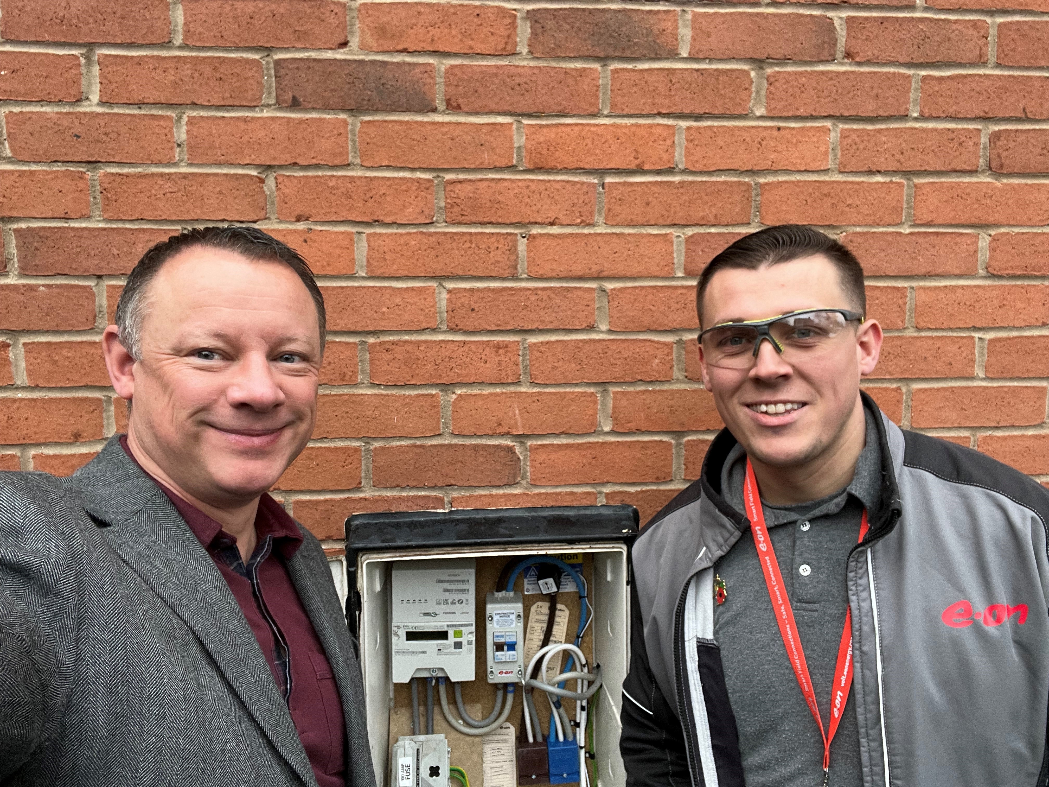 A photo of an engineer next to a smart meter and comms hub