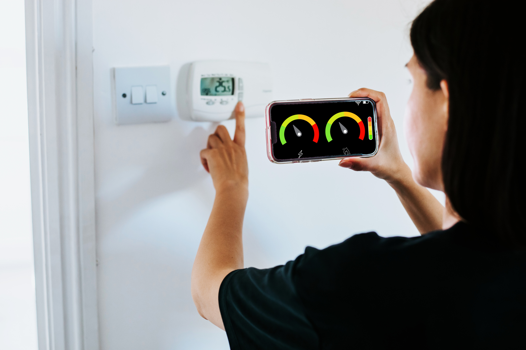 Woman pouring hot water in background whilst smart meter shows energy reading